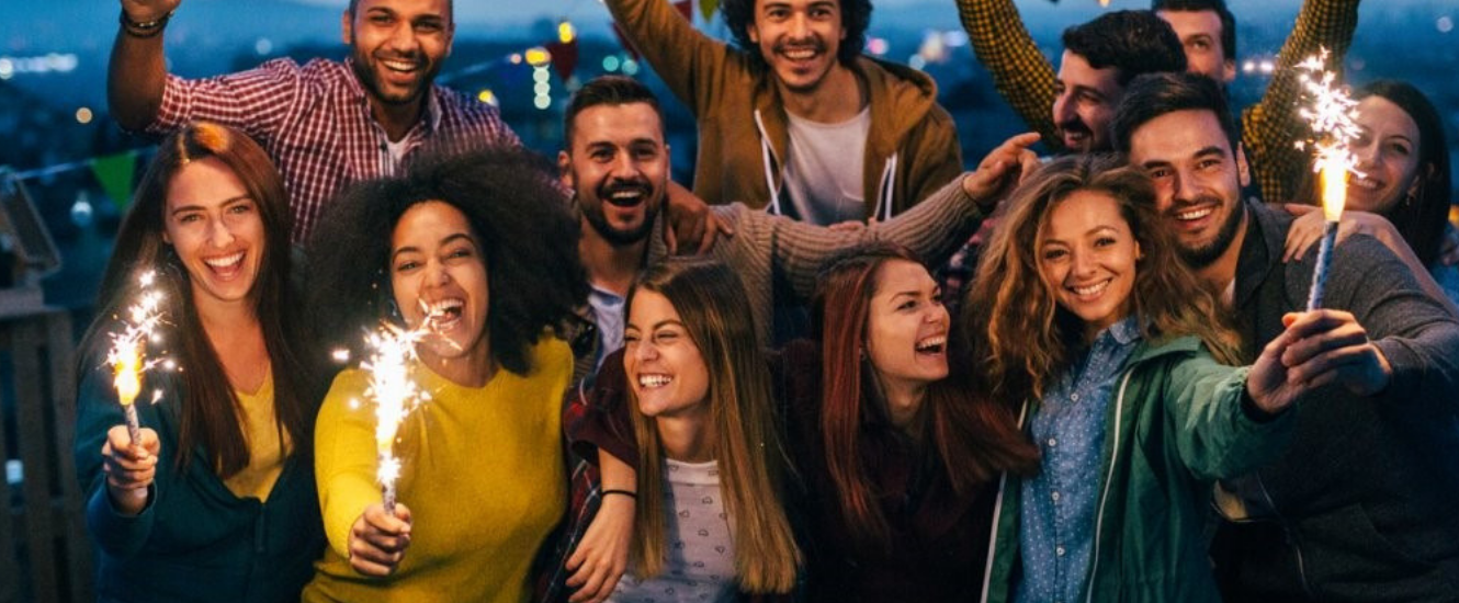 Group of people holding sparklers on rooftop